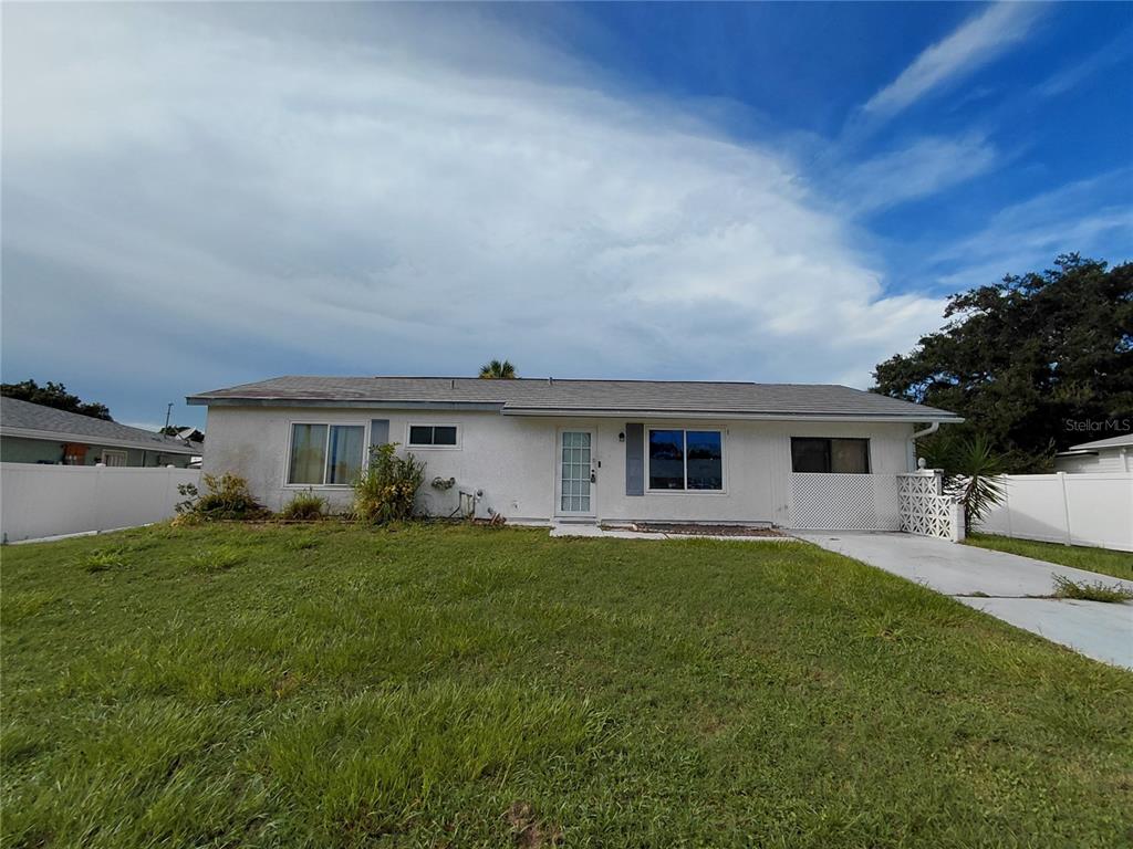 A single-story white house with a front lawn, driveway, and white vinyl privacy fence — 18292 MORRISSON AVENUE, PORT CHARLOTTE, FL