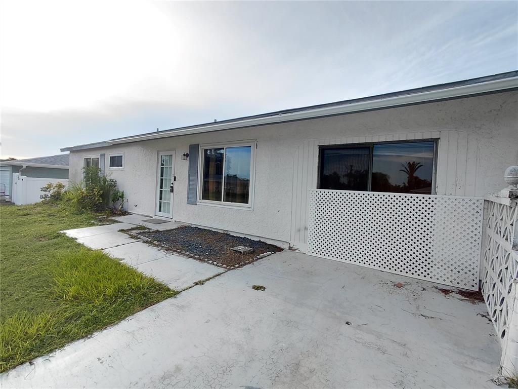 The exterior of a white, single-story house features a concrete driveway, lattice screen, and windows — 18292 MORRISSON AVENUE, PORT CHARLOTTE, FL