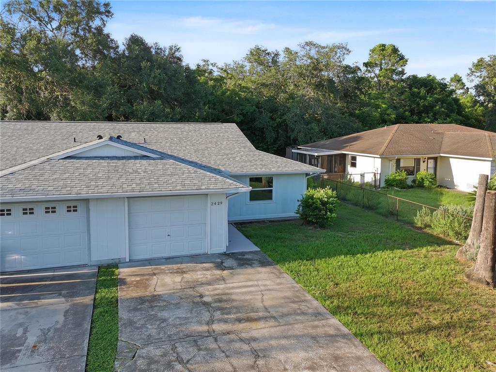 An aerial view shows the exterior of a light blue duplex with a concrete driveway — 2429 CENTENNIAL BOULEVARD, LEESBURG, FL