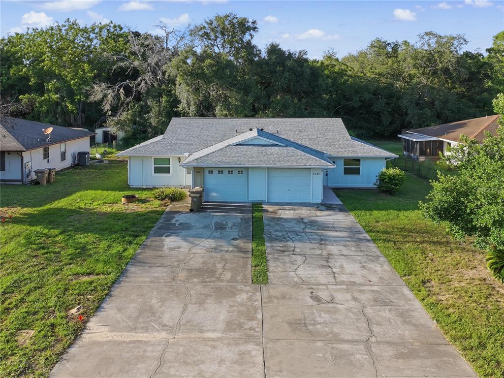 An exterior view of a single-story duplex with two garages and a shared concrete driveway — 2429 CENTENNIAL BOULEVARD, LEESBURG, FL
