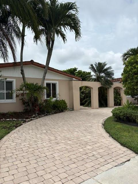 A paved driveway leads to a house with a tan exterior and an arched entryway — 9624 SW 79th Ter, Miami FL 33173, MIAMI, FL