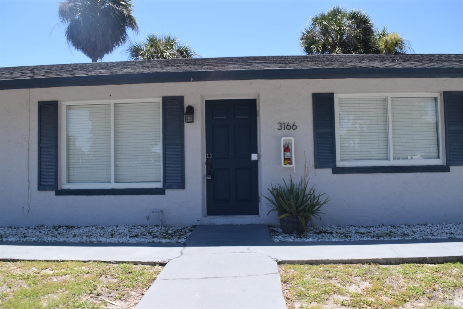 A single-story building exterior features a dark blue front door, shutters, and a fire extinguisher — 3166 Melaleuca Road, West Palm Beach FL 33406, WEST PALM BEACH, FL