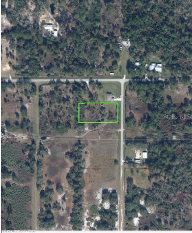 An aerial view shows a rectangular plot of land outlined in green within a wooded area — 1628 S ELLER ROAD, AVON PARK, FL