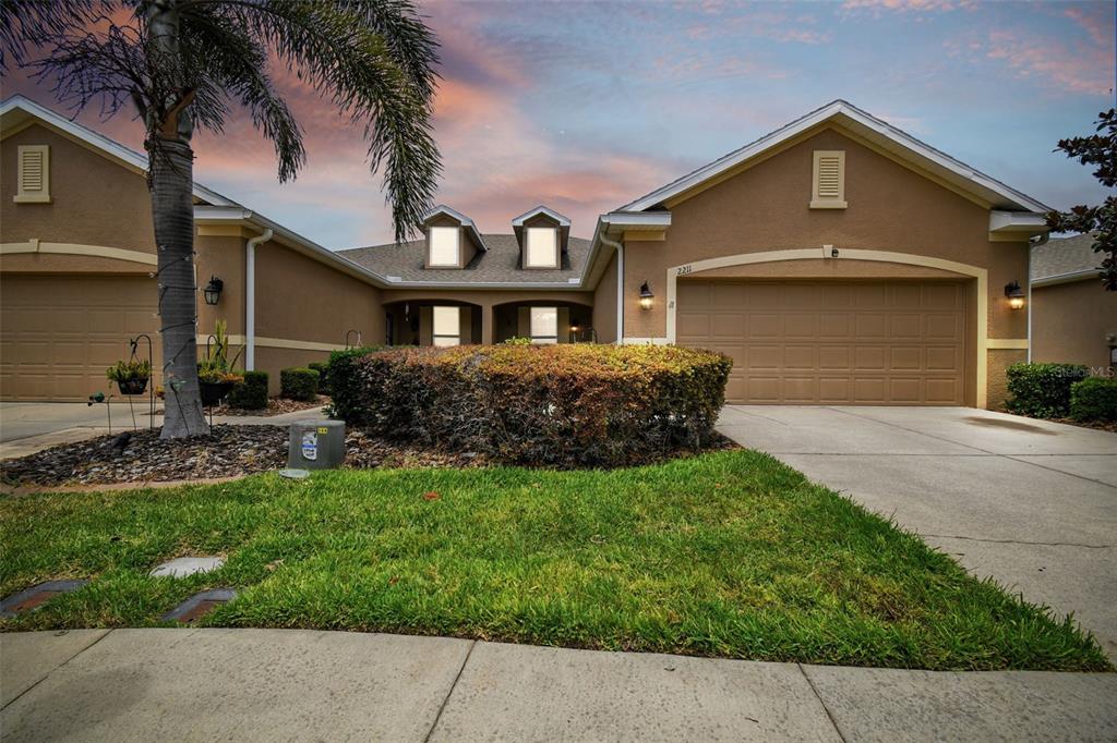 A tan stucco house with a two-car garage and a palm tree in the front yard — 2211 BARRACUDA COURT, HOLIDAY, FL