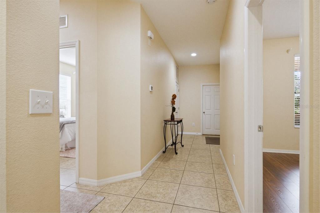 A tiled hallway leads to a doorway with a small decorative table against the wall — 2211 BARRACUDA COURT, HOLIDAY, FL