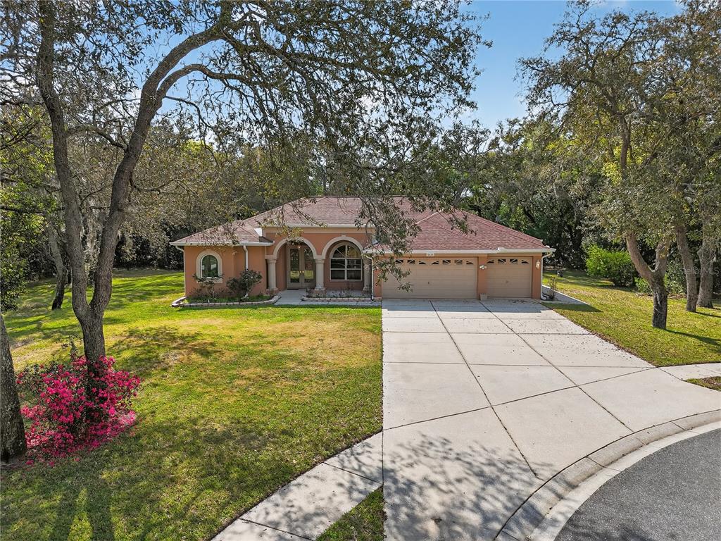 A single-story house with a terracotta exterior, arched entryway, and a three-car garage — 14024 WARM SPRINGS COURT, HUDSON, FL
