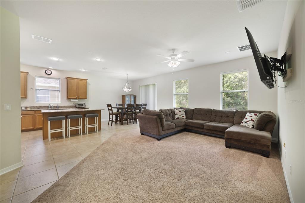 An open-concept living room and kitchen with tile flooring, carpet, and a large sectional sofa — 3773 MOON DANCER PLACE, ST CLOUD, FL