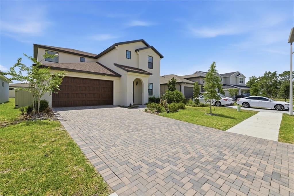 A two-story house with a paved driveway, a two-car garage, and a light-colored exterior — 82 HILLSHIRE PLACE, SPRING HILL, FL