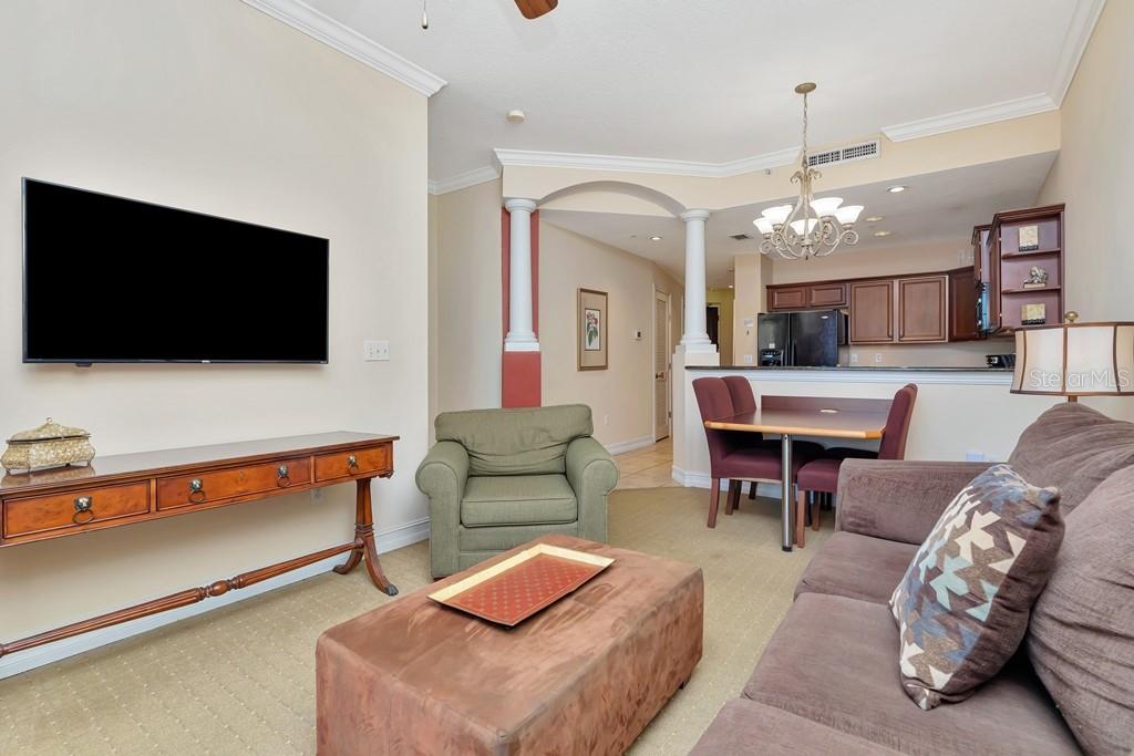 A living room with a television, sofa, armchair, and an adjacent dining area and kitchen — 13941 CLUBHOUSE DRIVE UNIT 103, TAMPA, FL