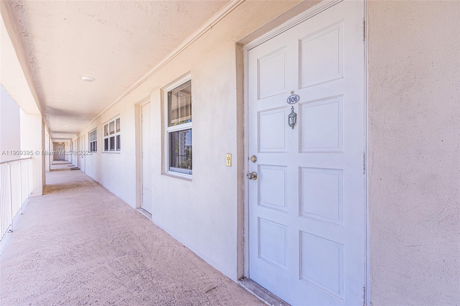 An exterior walkway leads past several white doors and windows of an apartment building — 2671 S Course Dr # 506, Pompano Beach FL 33069, POMPANO BEACH, FL