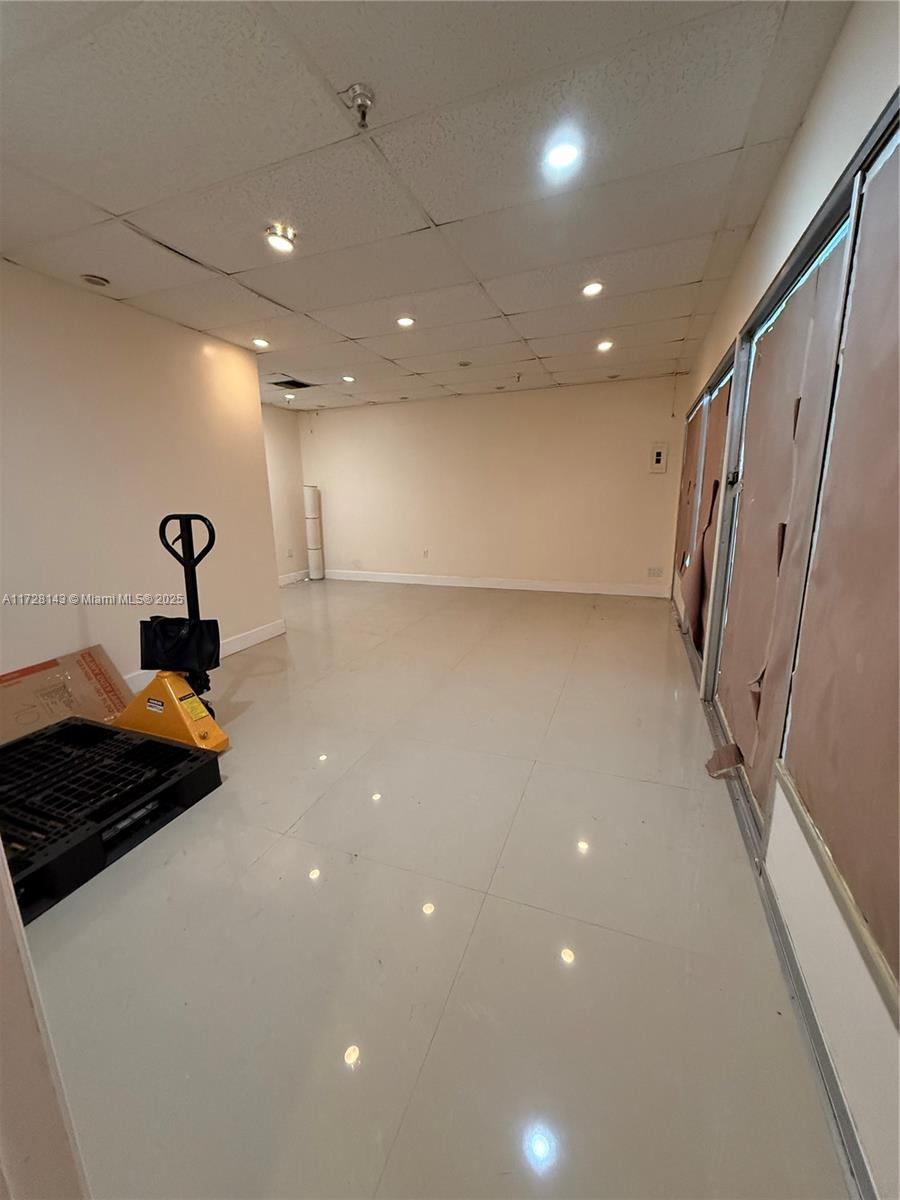 An empty commercial room features white tile flooring, a drop ceiling with recessed lighting, and windows — 777 NW 72nd Ave # 2131, Miami FL 33126, MIAMI, FL