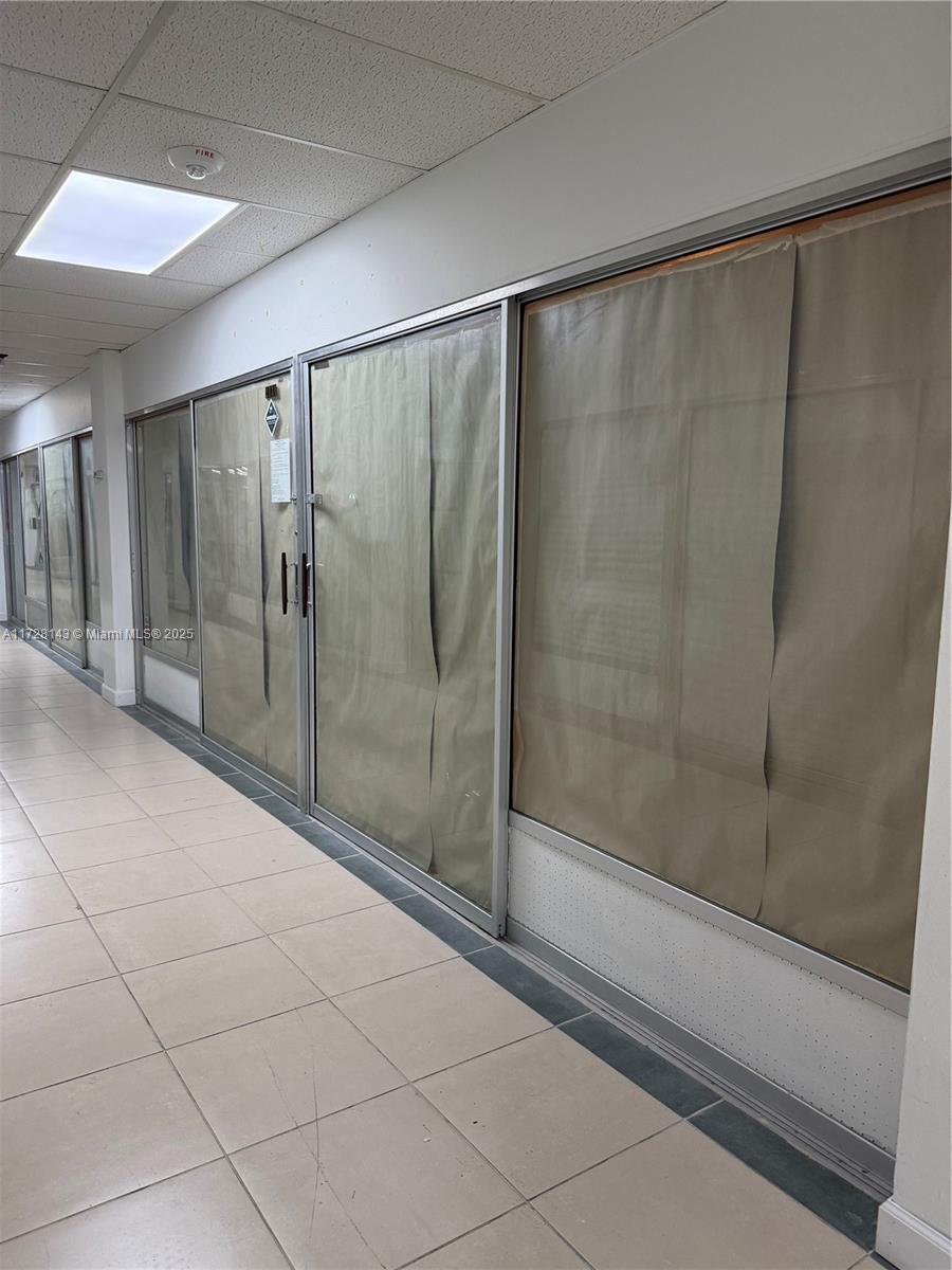 A hallway features tiled floors and glass storefronts covered with brown paper — 777 NW 72nd Ave # 2131, Miami FL 33126, MIAMI, FL