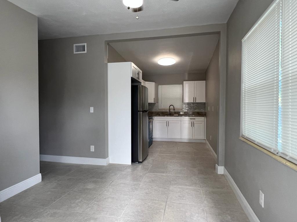 A kitchen with white cabinets and stainless steel appliances opens into a tiled dining area — 3990 Plum Tree Drive, Lake Worth FL 33462, LAKE WORTH, FL