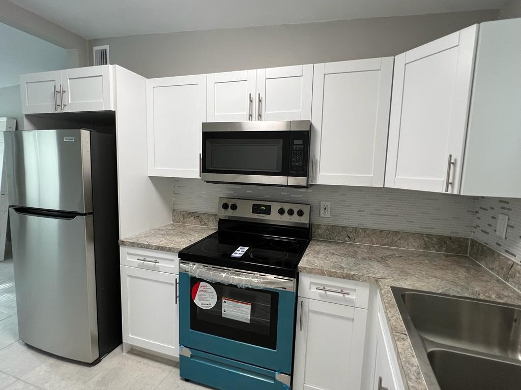 A kitchen with white shaker cabinets, stainless steel appliances, and a stone-look laminate countertop — 3990 Plum Tree Drive, Lake Worth FL 33462, LAKE WORTH, FL