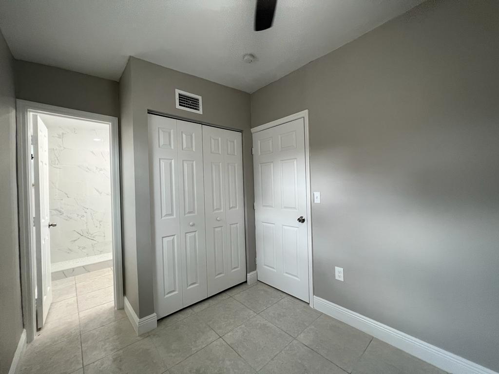 A room with tile flooring, a closet with bi-fold doors, and an adjacent bathroom doorway — 3990 Plum Tree Drive, Lake Worth FL 33462, LAKE WORTH, FL