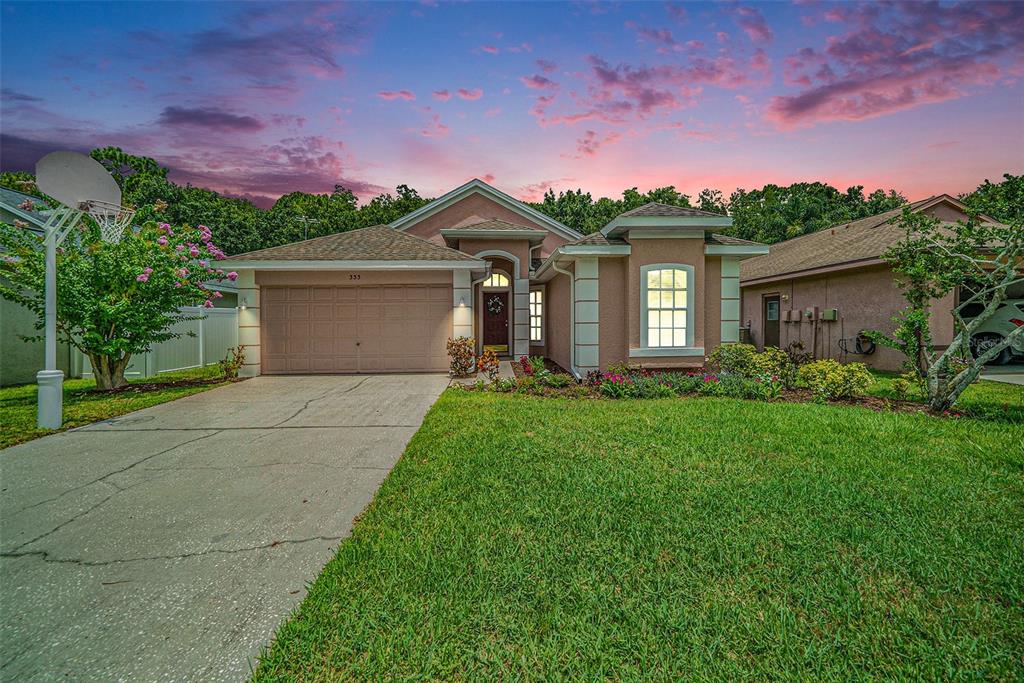 A single-story house with a tan stucco exterior, a two-car garage, and a manicured lawn — 333 TAVERNIER DRIVE, OLDSMAR, FL