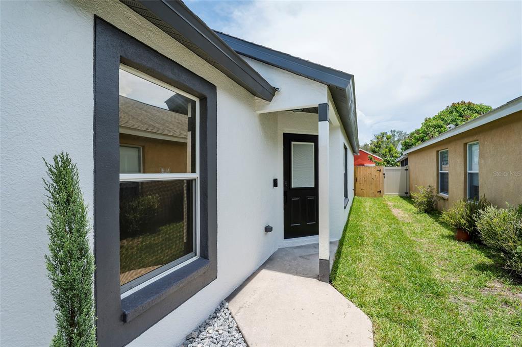 A side view of a white house with a dark-framed window and door — 7522 OXFORD GARDEN CIRCLE, APOLLO BEACH, FL