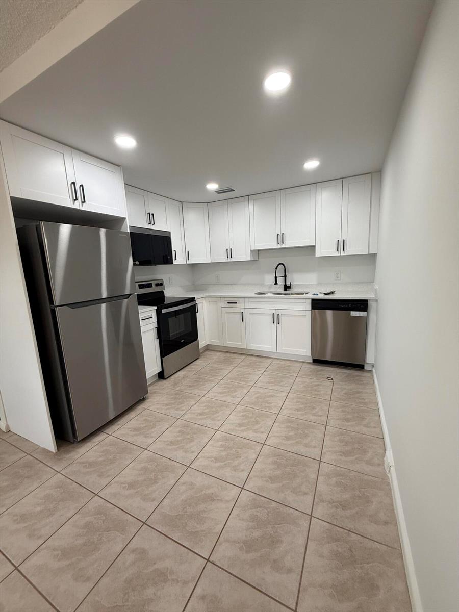 A kitchen features white cabinets, stainless steel appliances, and light-colored tile flooring — 3089 Yarmouth E # 3089, Boca Raton FL 33434, BOCA RATON, FL
