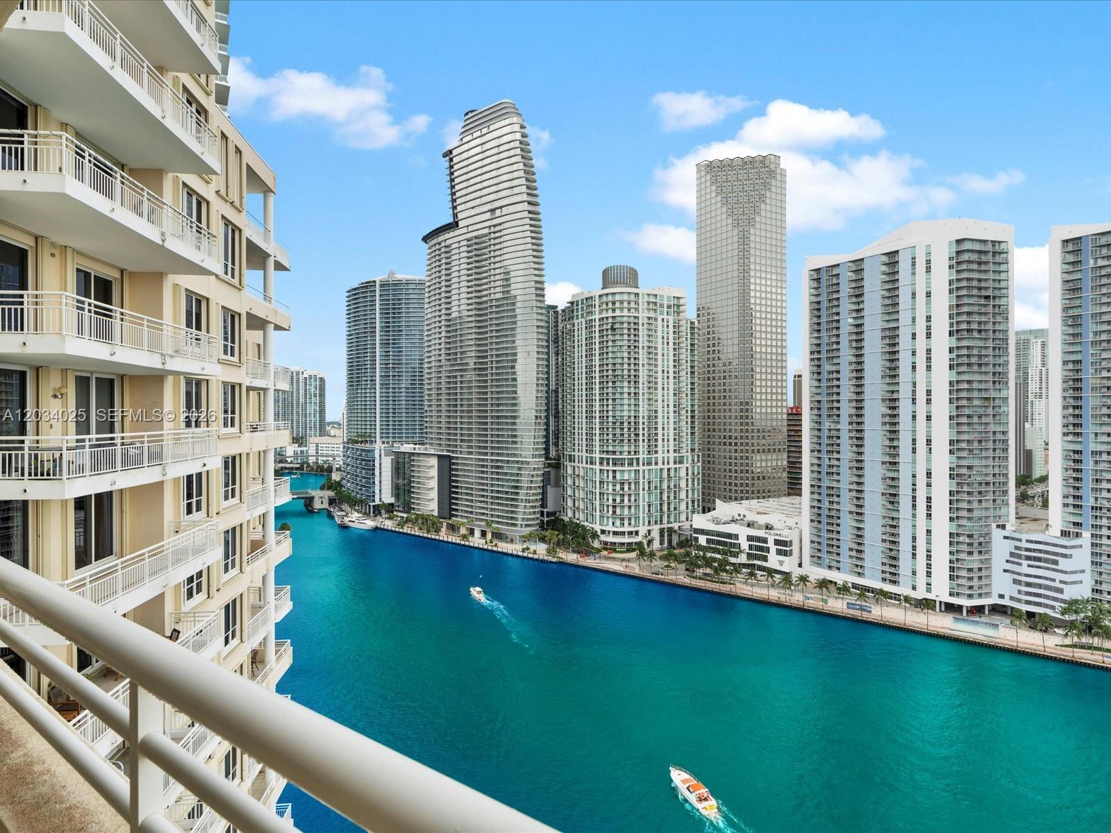 A high-angle view shows a balcony overlooking a turquoise river surrounded by tall skyscrapers — 888 Brickell Key Dr # 2510, Miami FL 33131, MIAMI, FL