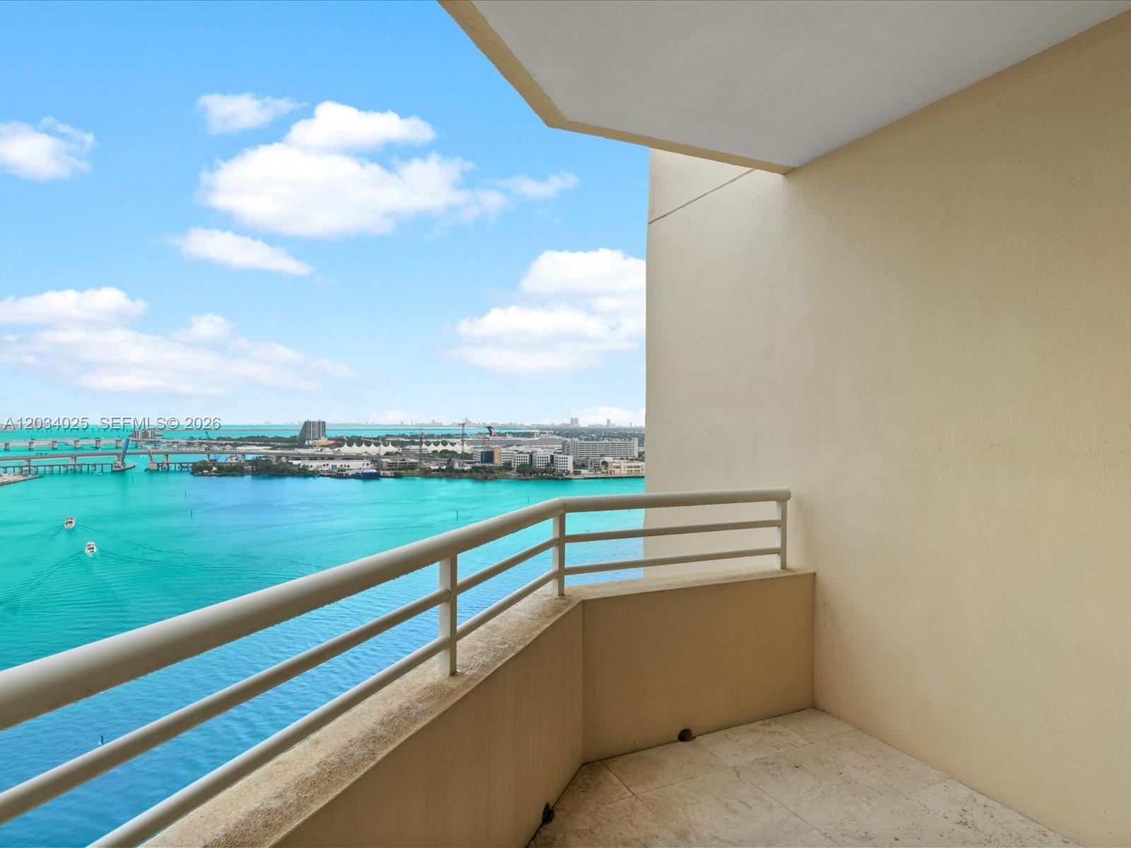 A balcony with a metal railing overlooks a blue bay and a city skyline — 888 Brickell Key Dr # 2510, Miami FL 33131, MIAMI, FL