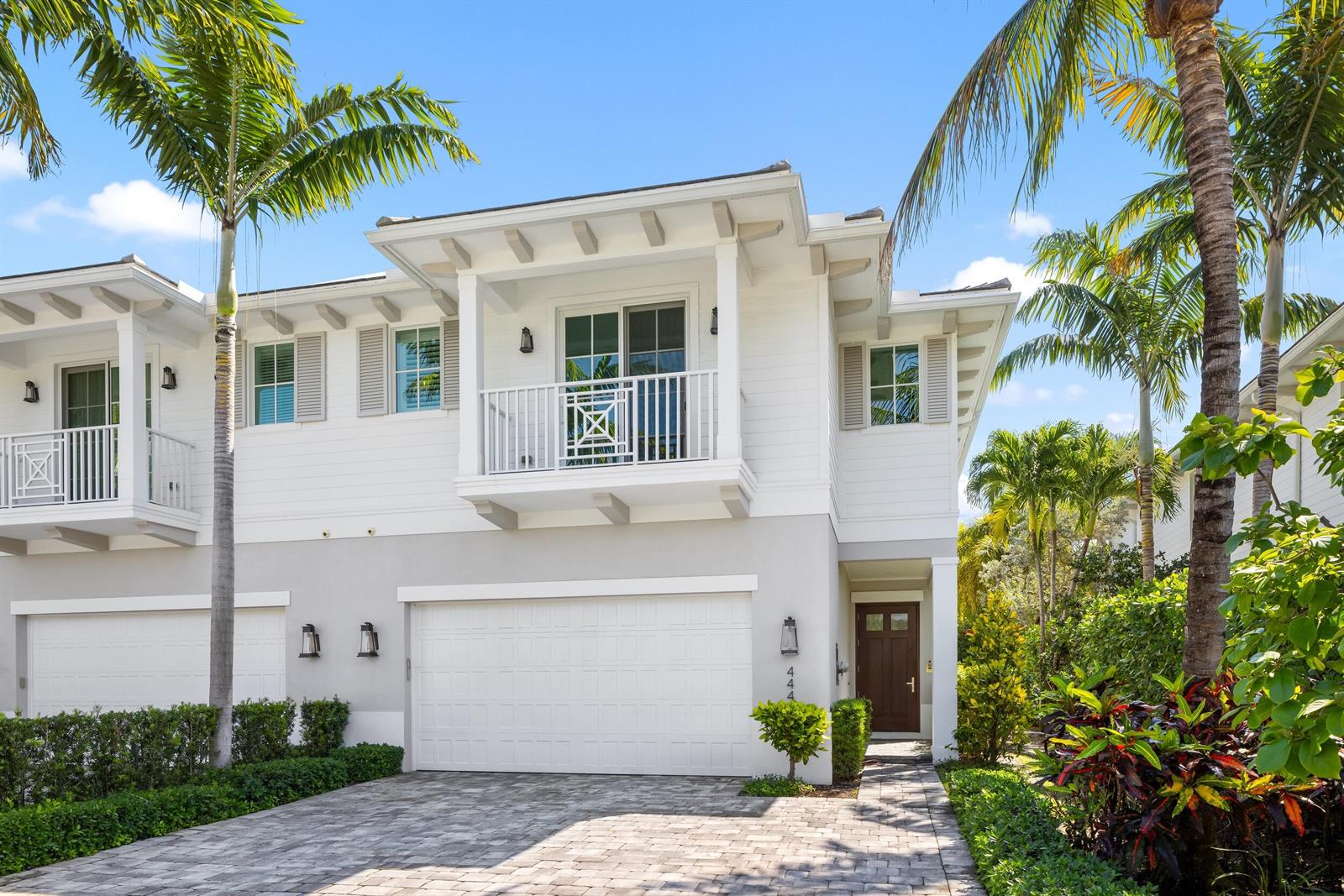 A two-story white townhouse with a garage, balcony, and palm trees under a clear sky — 444 NE Wavecrest Way, Boca Raton FL 33432, BOCA RATON, FL