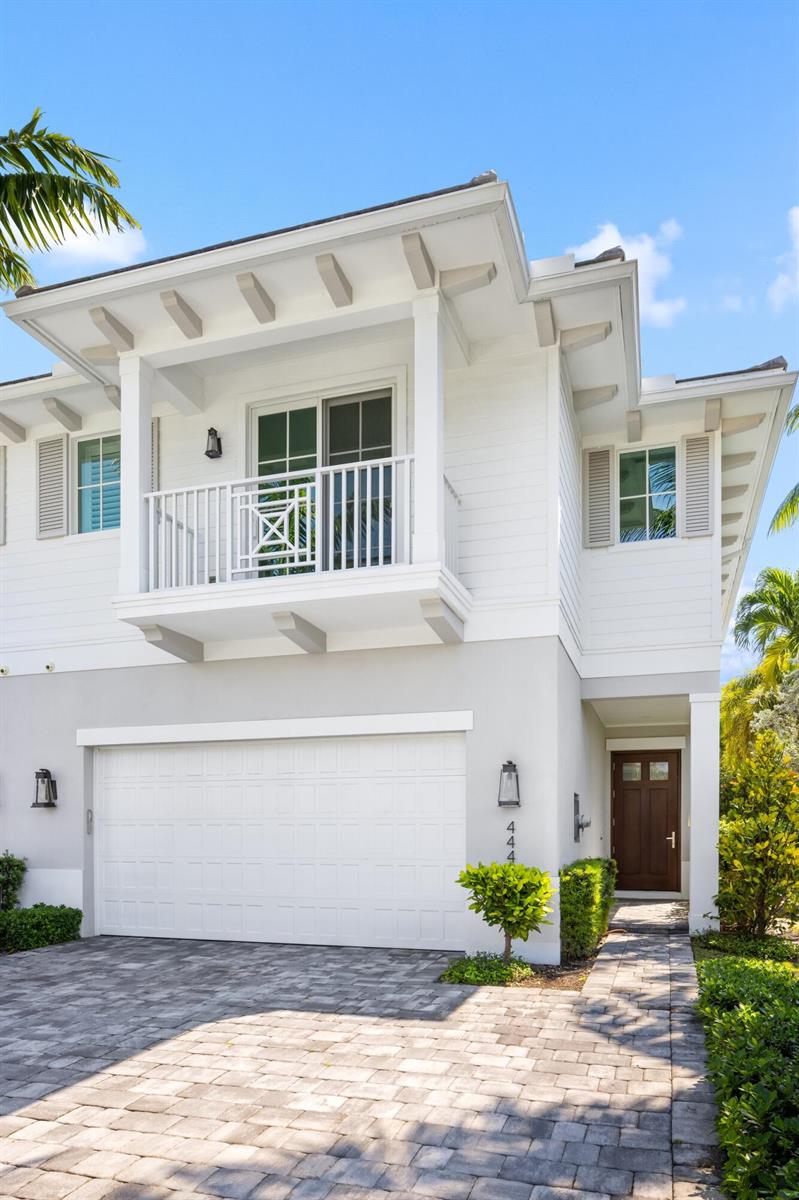 A two-story house exterior features a white balcony, a garage, and a paved driveway — 444 NE Wavecrest Way, Boca Raton FL 33432, BOCA RATON, FL