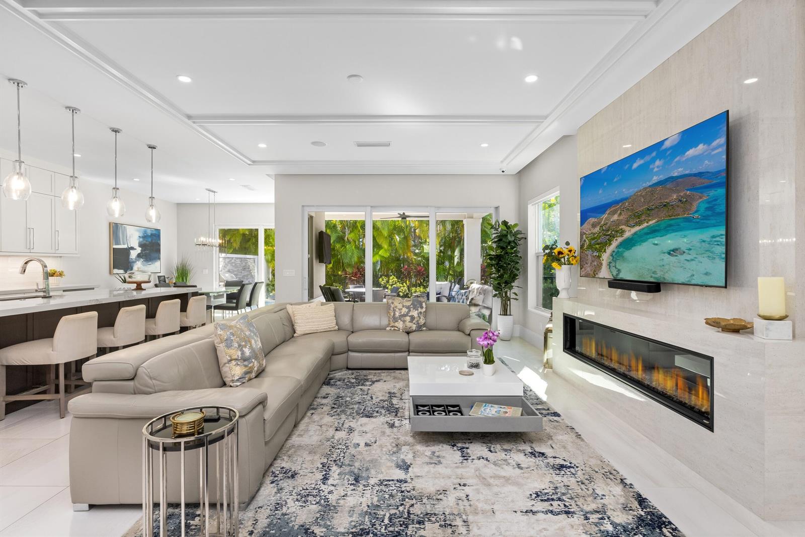 A modern living room features a large sectional sofa, a fireplace, and an open kitchen — 444 NE Wavecrest Way, Boca Raton FL 33432, BOCA RATON, FL