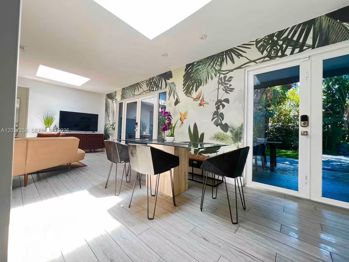 A dining area features a glass table, modern chairs, and a tropical mural wall — 424 NE 28th Dr, Wilton Manors FL 33334, WILTON MANORS, FL