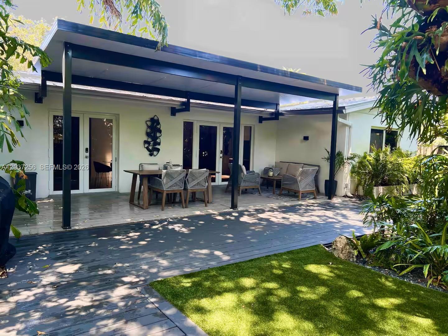 A covered patio with a wooden deck, outdoor furniture, and a small patch of grass — 424 NE 28th Dr, Wilton Manors FL 33334, WILTON MANORS, FL