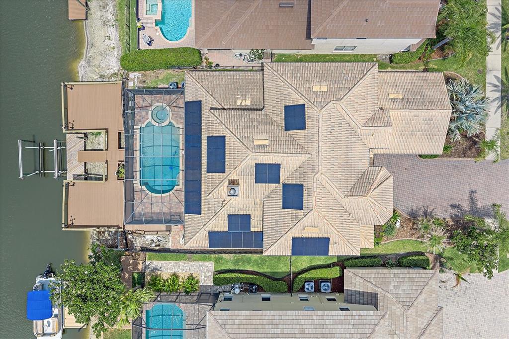An aerial view shows a house with a tiled roof, solar panels, and a pool — 18046 COZUMEL ISLE DRIVE, TAMPA, FL