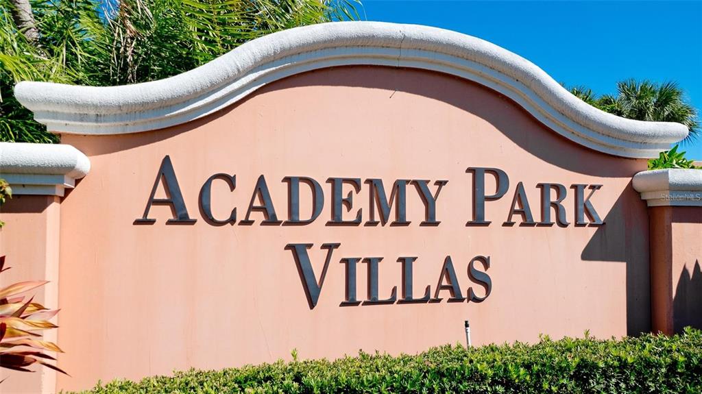 A beige stucco monument sign displays the words Academy Park Villas in dark lettering — 5429 46TH COURT W, BRADENTON, FL