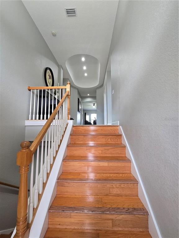 A wooden staircase leads to an upper hallway featuring a recessed ceiling with spotlights — 5429 46TH COURT W, BRADENTON, FL