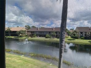 A view from a screened balcony overlooking a pond with a fountain and apartment buildings — 5555 ASHTON WAY UNIT 5555, SARASOTA, FL