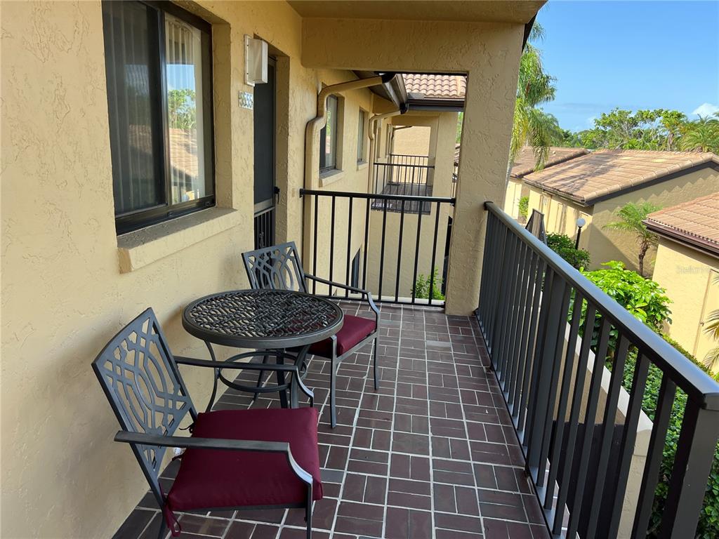 A covered balcony features a small table with two chairs and tiled flooring — 5555 ASHTON WAY UNIT 5555, SARASOTA, FL