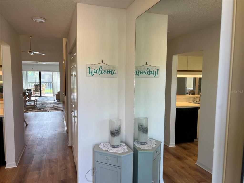 An entryway features a light blue cabinet, a mirror, and a welcome sign on the wall — 5555 ASHTON WAY UNIT 5555, SARASOTA, FL