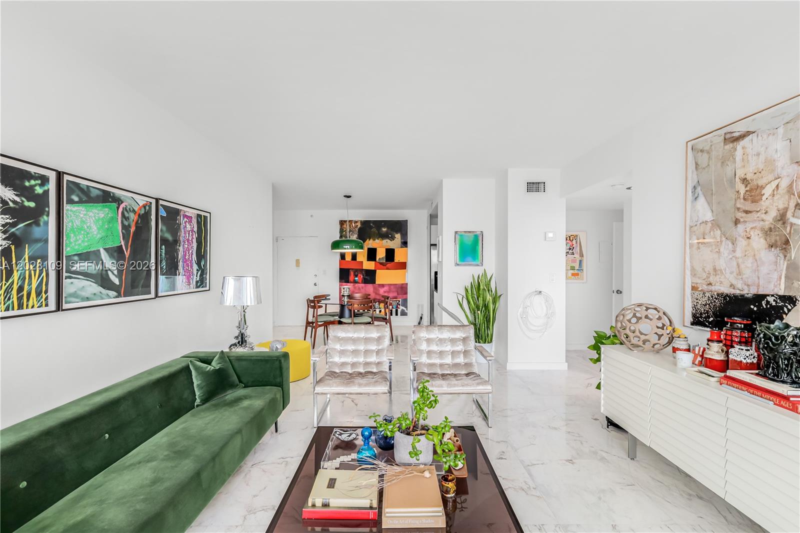 A living room features a green velvet sofa, two metallic chairs, and white marble flooring — 3 Island Ave # 11B, Miami Beach FL 33139, MIAMI BEACH, FL