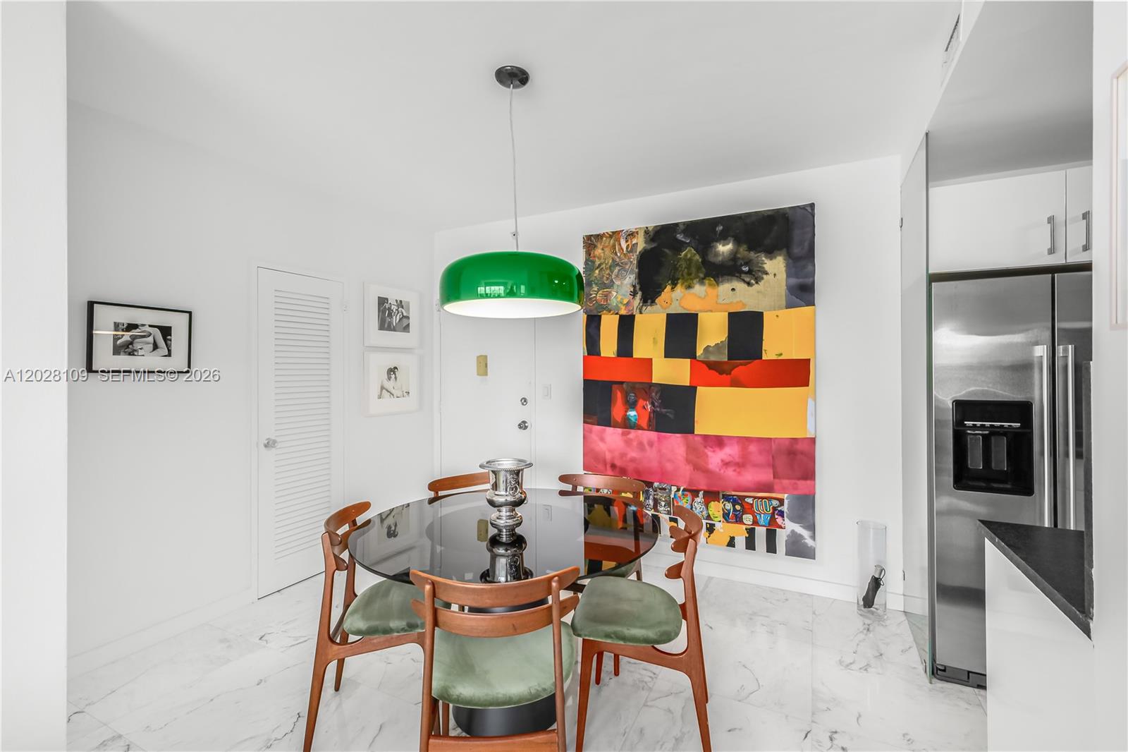 A dining area features a glass table, green chairs, a green pendant light, and artwork — 3 Island Ave # 11B, Miami Beach FL 33139, MIAMI BEACH, FL