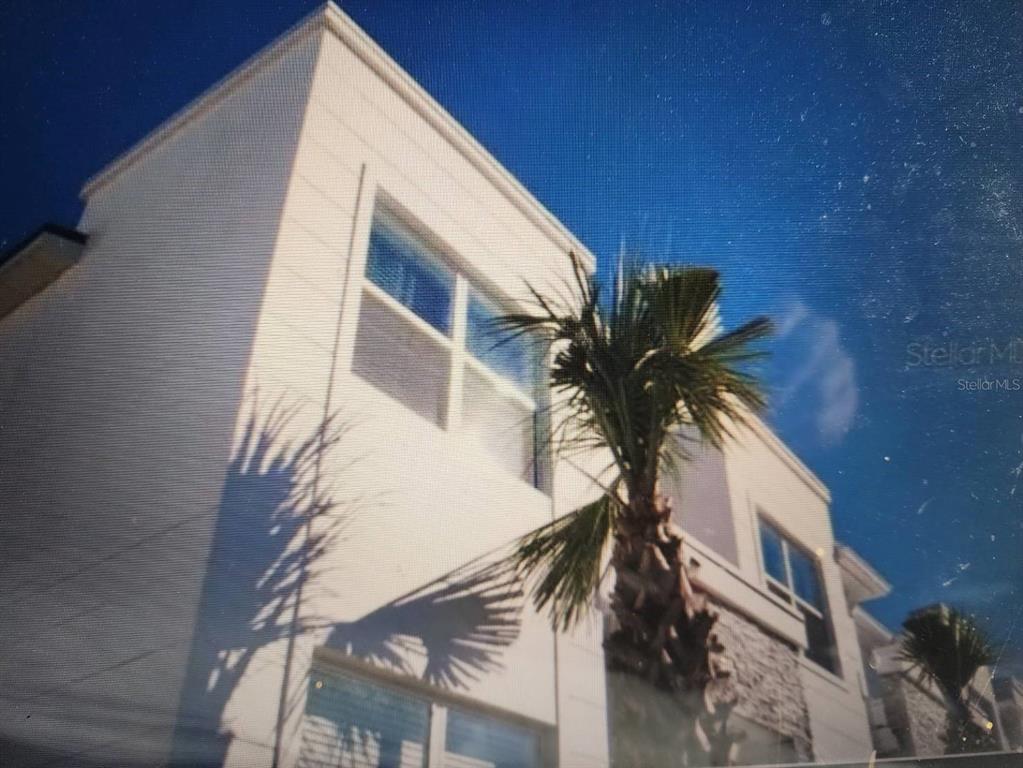A low-angle exterior view of a modern white building with a palm tree in front — 1393 PEACEFUL NATURE WAY, CLERMONT, FL