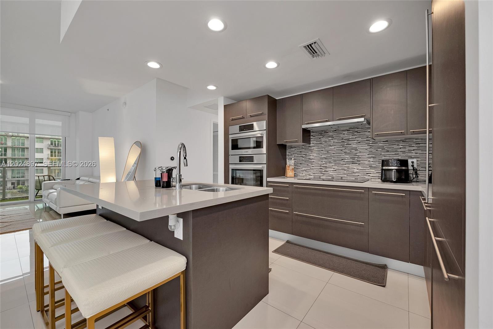 A modern kitchen features dark wood cabinetry, a quartz island, and stainless steel appliances — 7825 NW 107th Ave # 507, Doral FL 33178, DORAL, FL