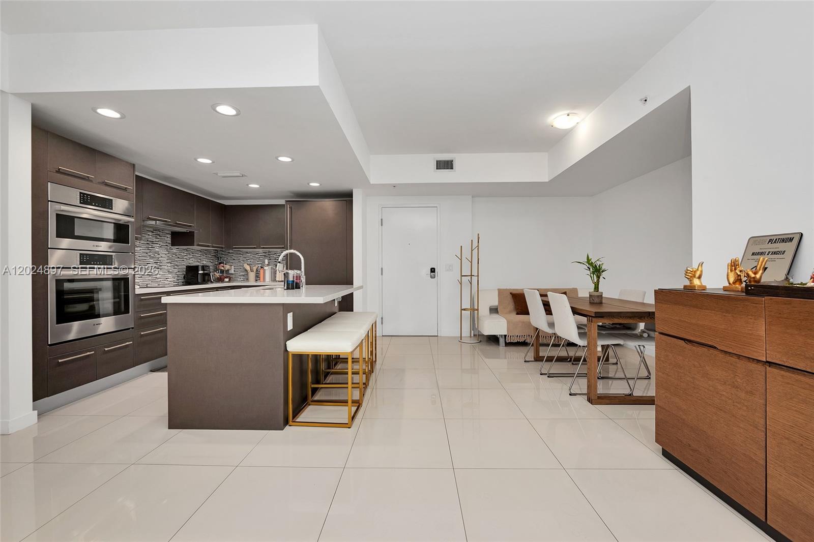 A modern kitchen with dark cabinetry and a white island sits beside a dining area — 7825 NW 107th Ave # 507, Doral FL 33178, DORAL, FL