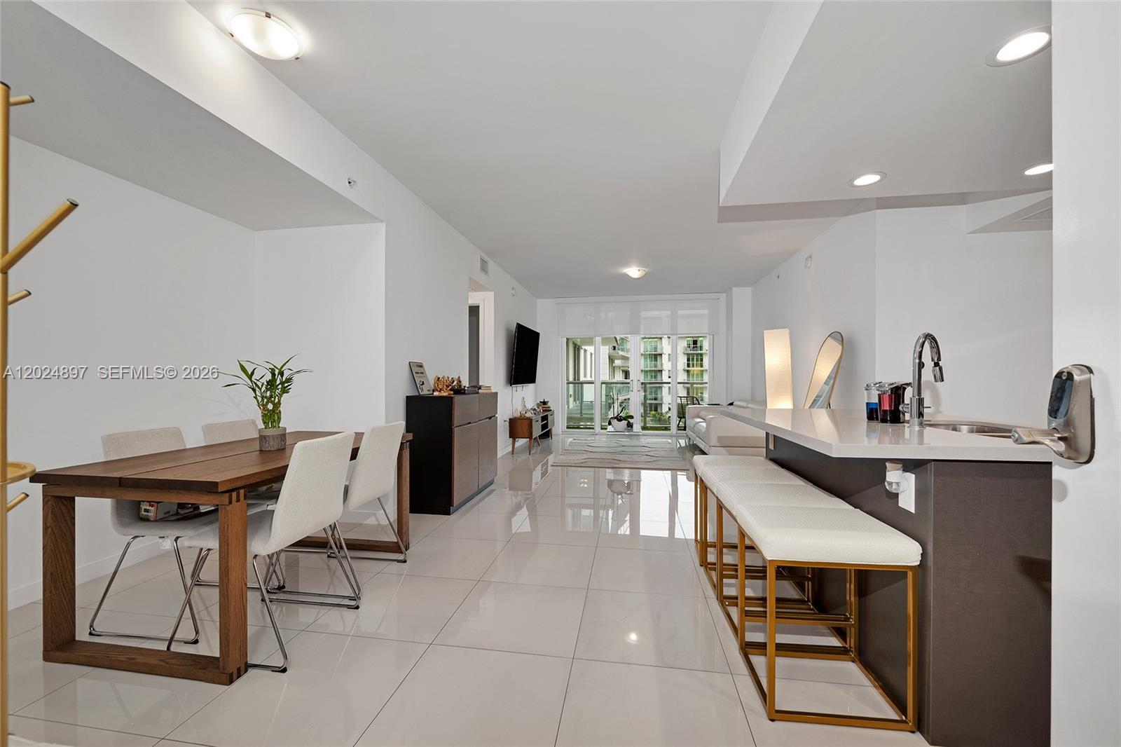 A modern open-concept living and dining area features white tile floors and a kitchen island — 7825 NW 107th Ave # 507, Doral FL 33178, DORAL, FL