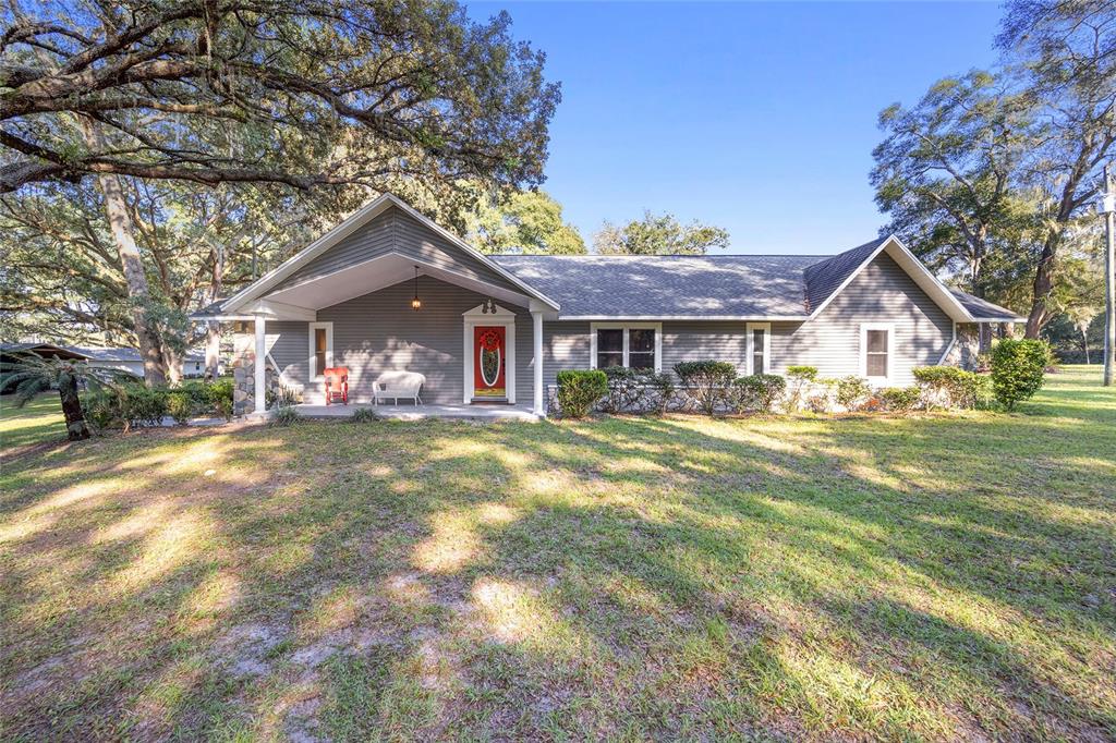 A single-story gray house with a covered front porch sits on a grassy lawn — 13315 NE 47TH AVENUE, ANTHONY, FL