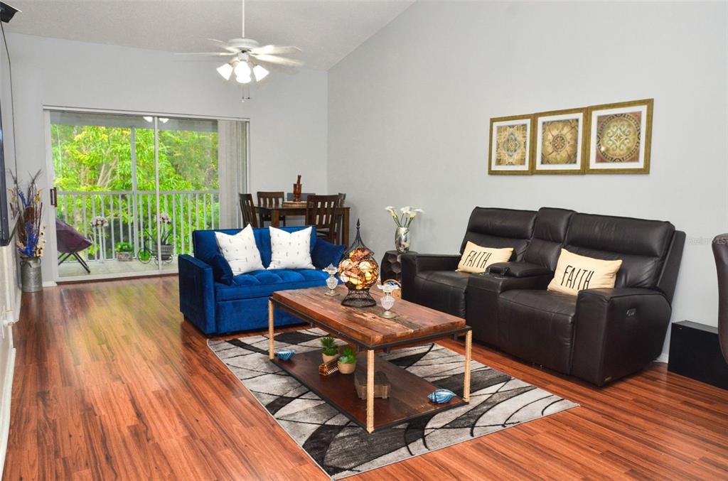 A living room features a blue loveseat, dark leather recliner, wood coffee table, and balcony access — 13801 TIMBERLAND DRIVE UNIT 201, ORLANDO, FL