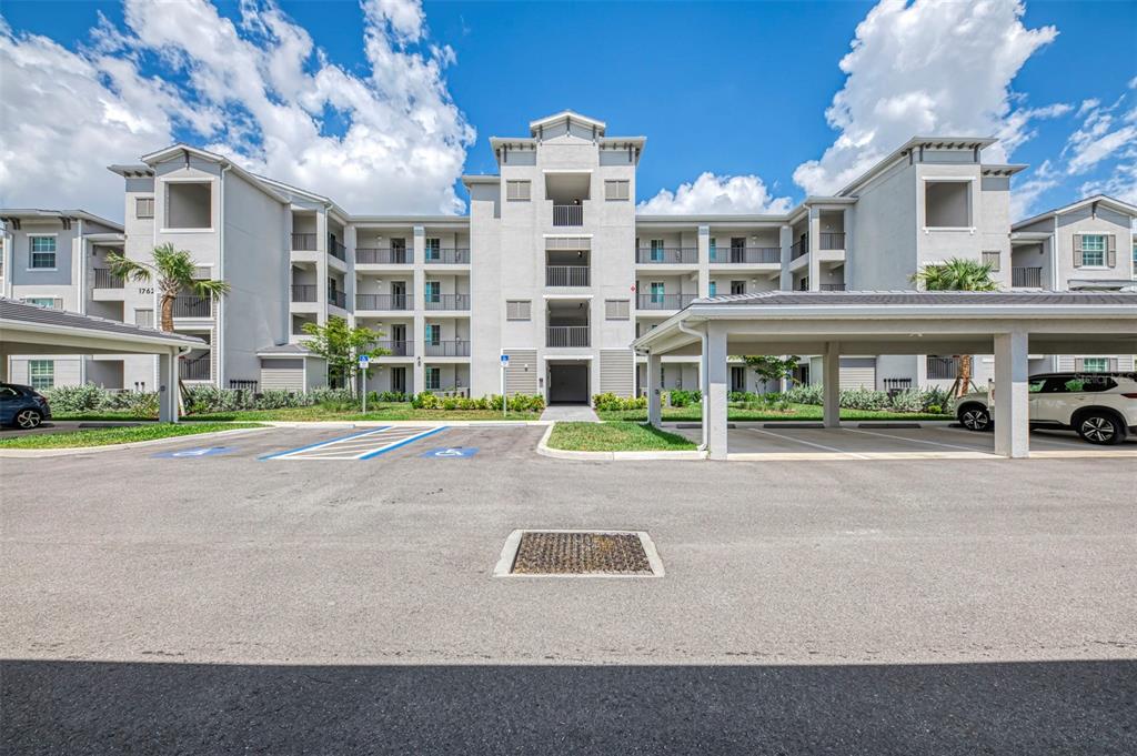 A multi-story apartment building with a covered parking structure and handicap-accessible parking spaces — 17625 OPAL SAND DRIVE UNIT 304, VENICE, FL