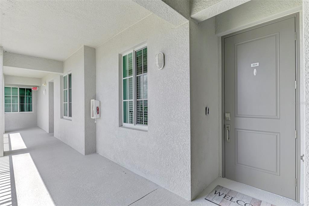 A gray door with the number 304 sits at the end of a white outdoor hallway — 17625 OPAL SAND DRIVE UNIT 304, VENICE, FL