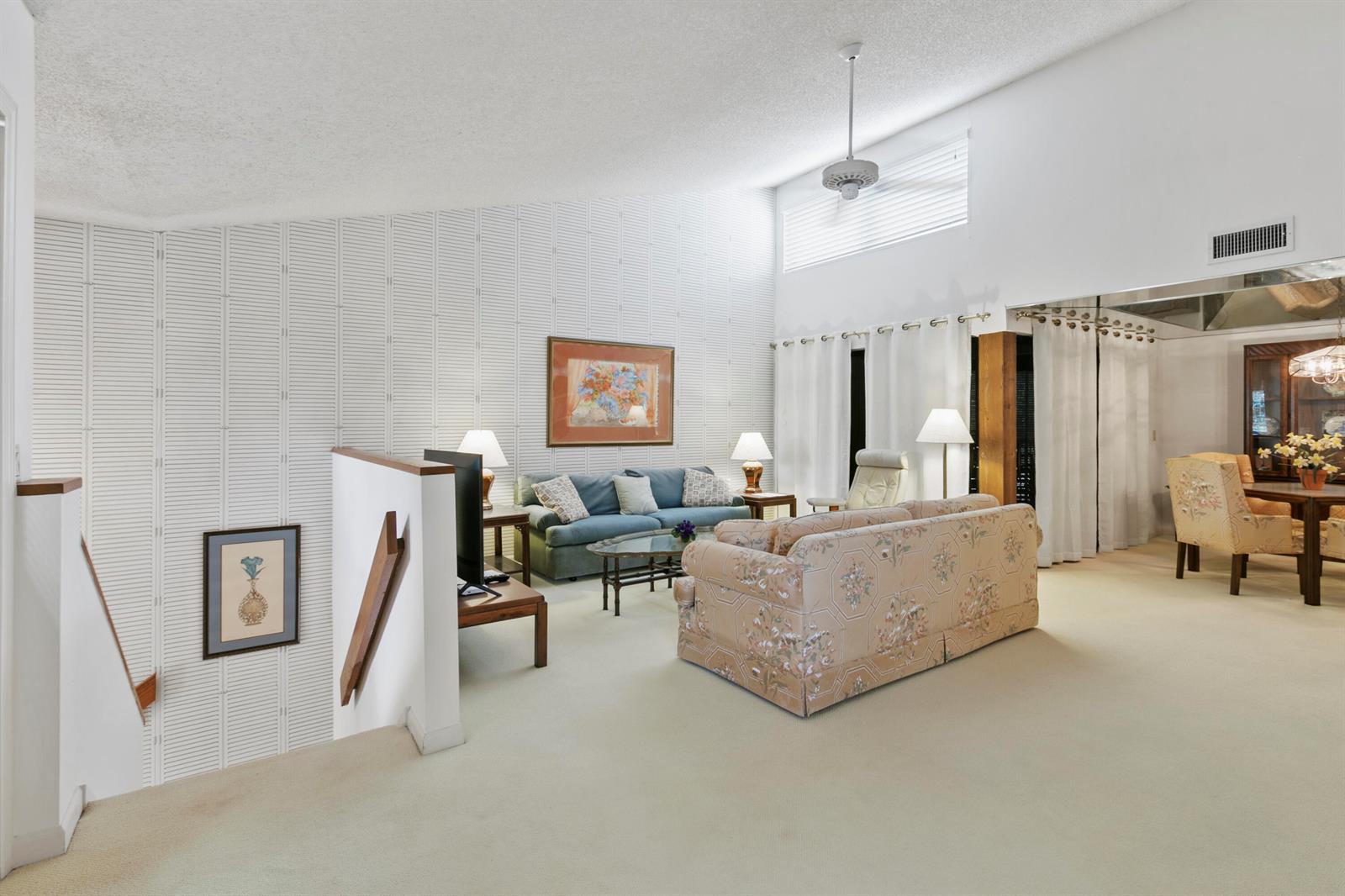 A living room with a vaulted ceiling, carpeted floors, and a blue sofa — 17110 Waterbend Drive # 219, Jupiter FL 33477, JUPITER, FL
