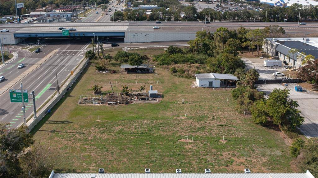 An aerial view shows a vacant lot with a small building and a highway overpass — 5711 W WATERS AVENUE, TAMPA, FL
