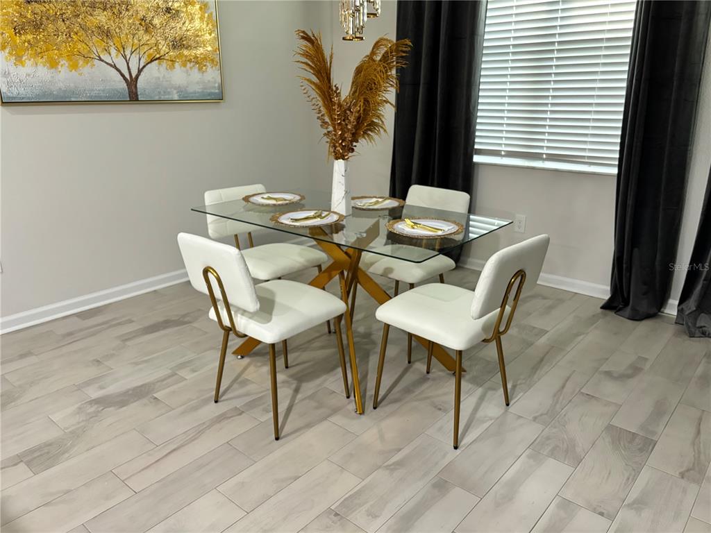 A dining room features a glass-topped table with gold legs and four white upholstered chairs — 10972 BRIGHTLEAF COURT, RIVERVIEW, FL