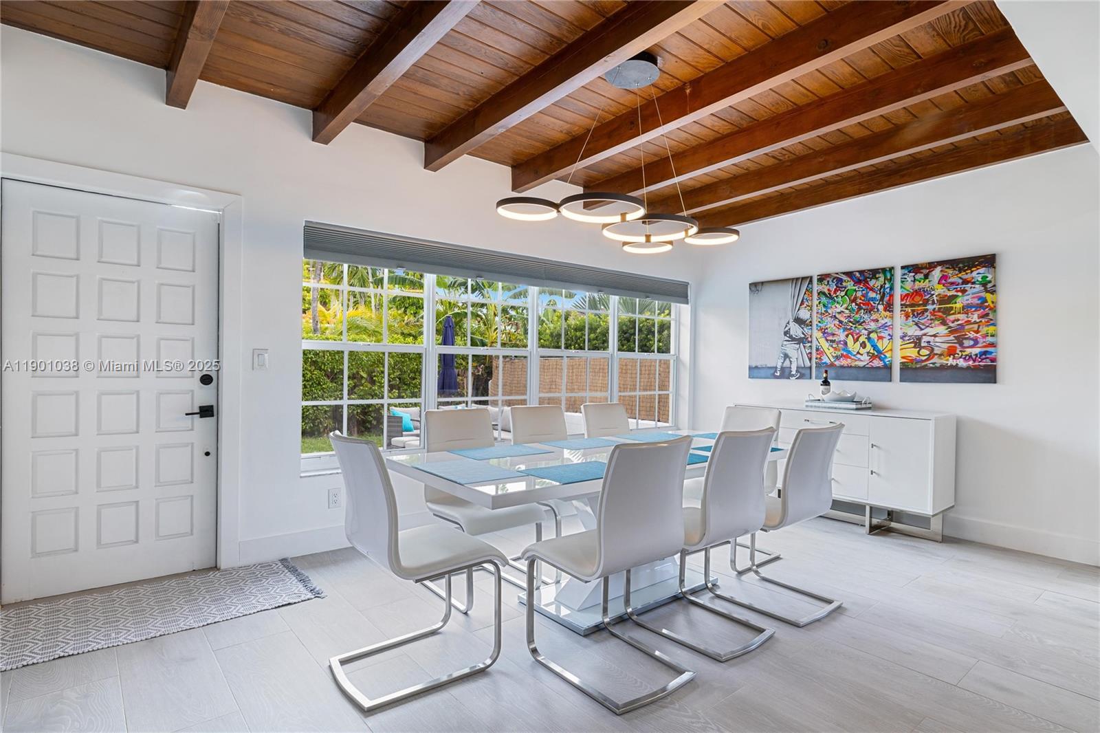 A dining room features a white table, modern chairs, wood-beamed ceilings, and large windows — 8926 Abbott Ave # 0, Surfside FL 33154, SURFSIDE, FL