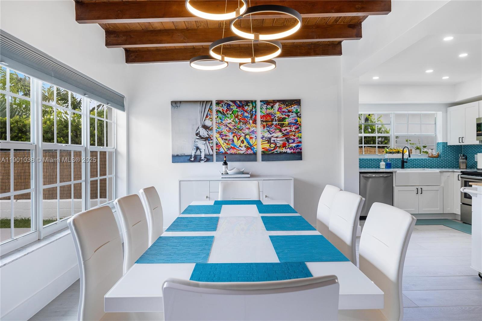 A dining room features a white table with blue placemats, modern lighting, and exposed ceiling beams — 8926 Abbott Ave # 0, Surfside FL 33154, SURFSIDE, FL